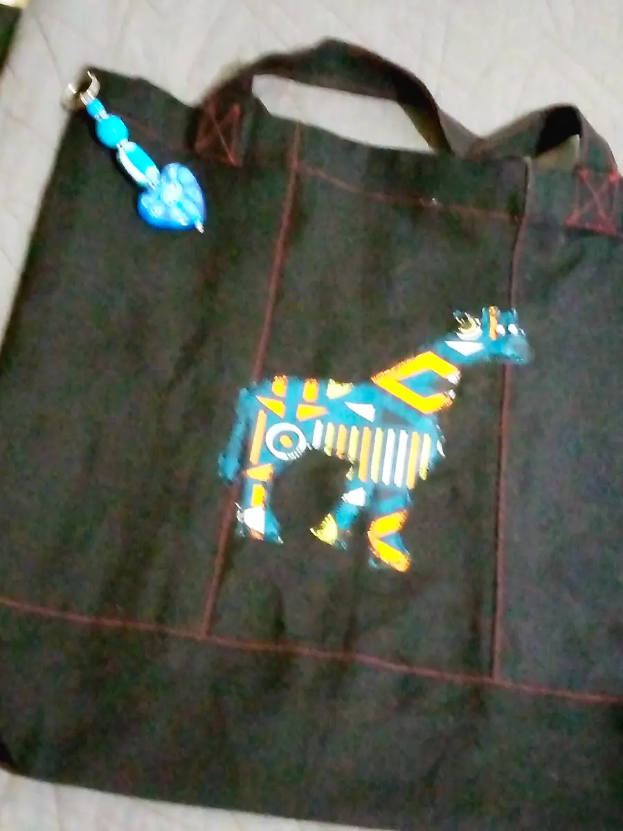 Black canvas tote with a giraffe appliqué in kitenge print and a beaded keyring charm