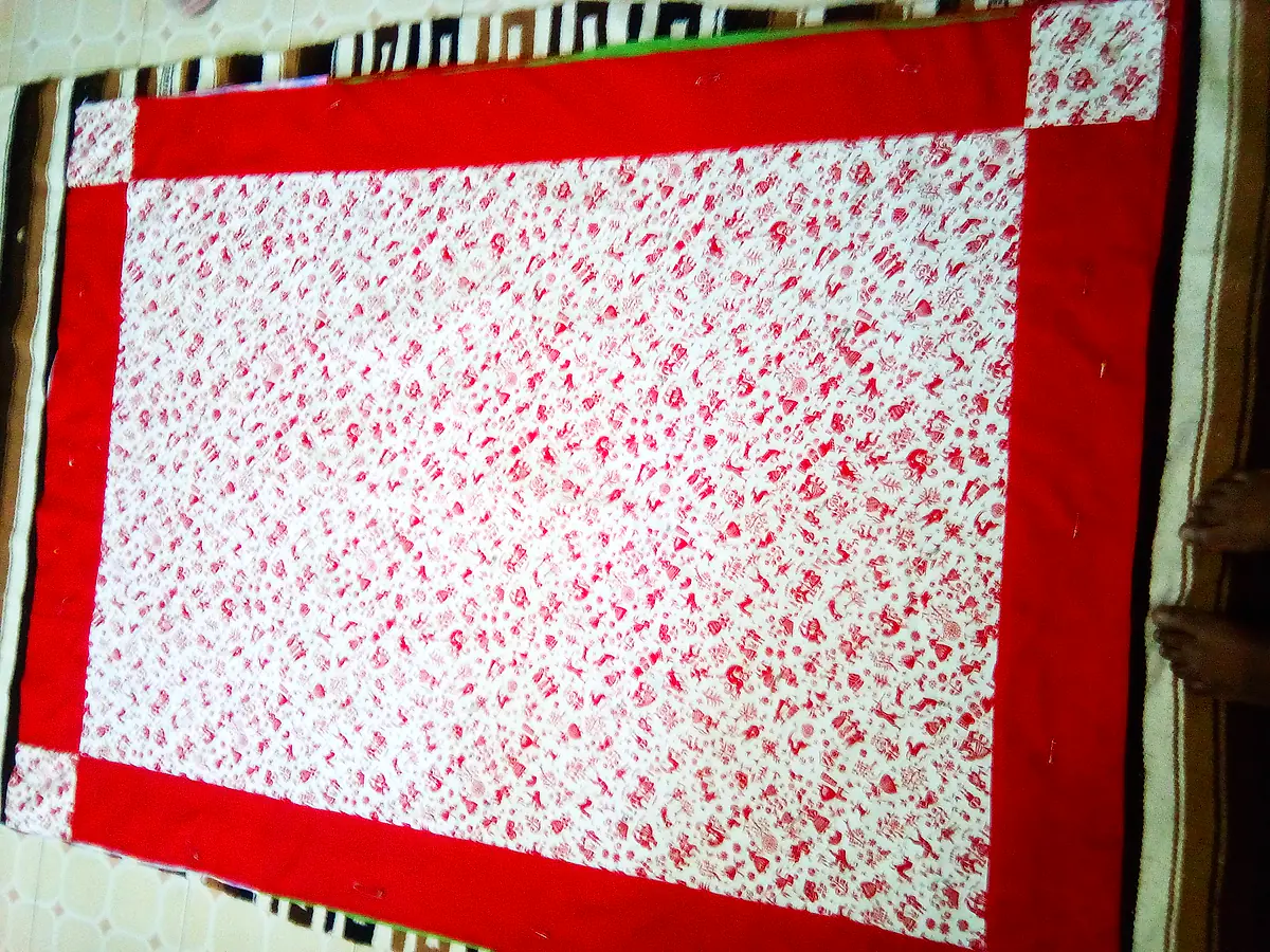 Bed quilt with a bold red border framing a red-and-white printed centre
