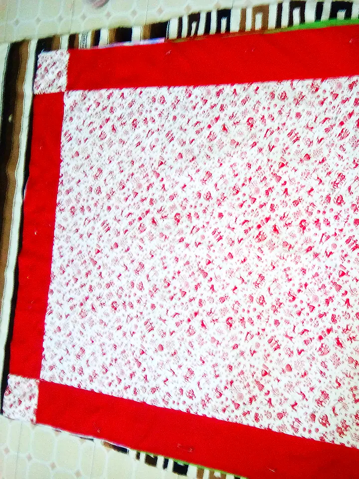 Bed quilt with a bold red border framing a red-and-white printed centre