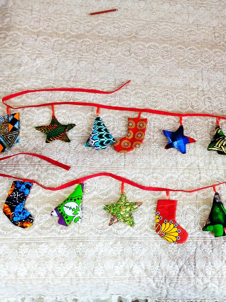 Two garlands of kitenge stars, trees and stockings on red ribbon