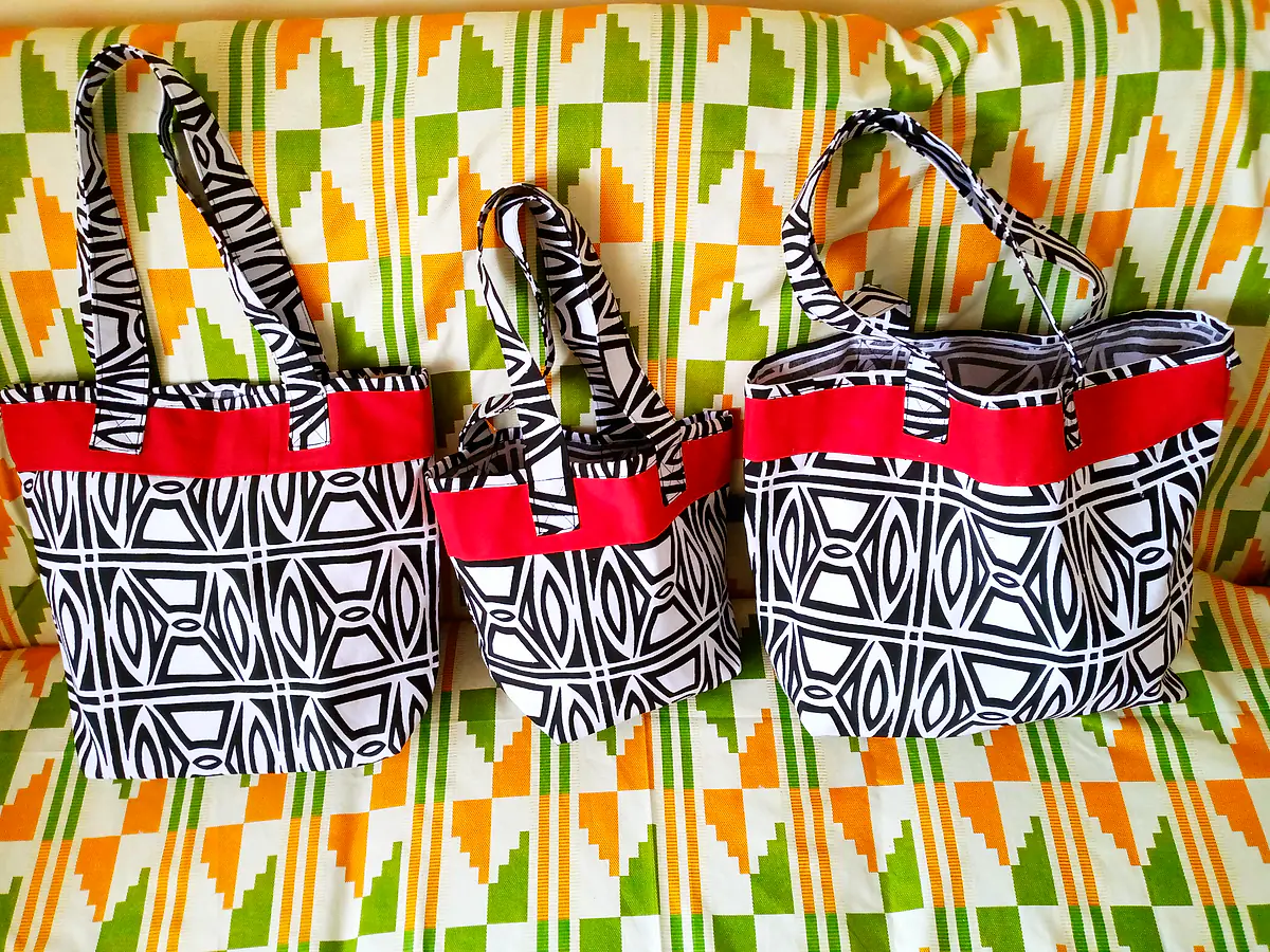 Three matching totes in large, medium and small sizes, in a black-and-white print with red trim