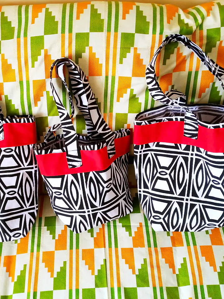 Three matching totes in large, medium and small sizes, in a black-and-white print with red trim