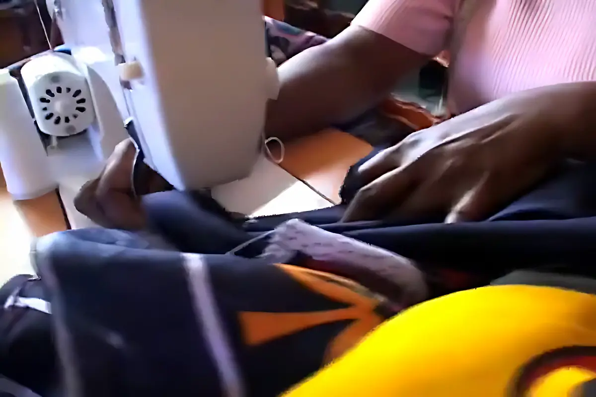 Hands guiding kanga fabric through a sewing machine