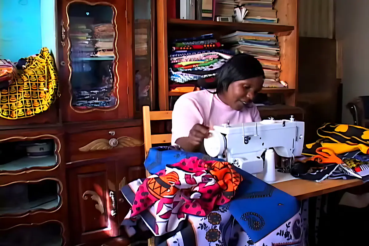 Mary at her sewing machine surrounded by colourful kanga fabrics