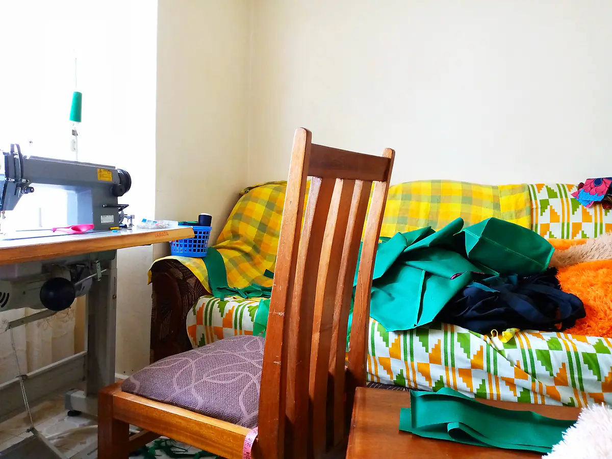 Mary’s sewing workshop with a machine and stacks of fabric